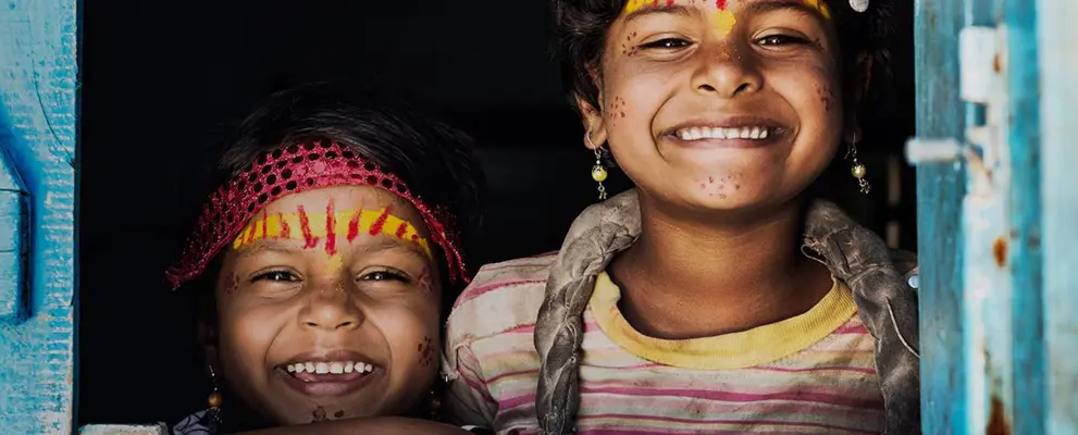 Two children smiling through wooden door
