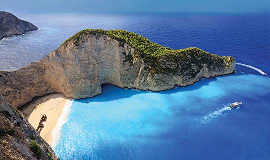 A vivid blue sea with golden sand and large cliff